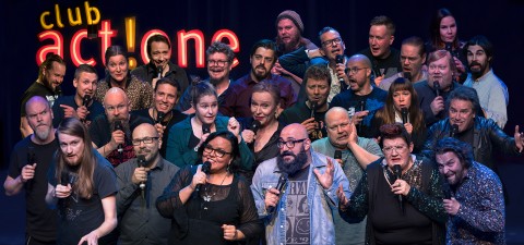 Suuri joukko ihmisiä, joilla on kädessään mikrofonit, laulaa yhdessä lavalla neonkyltin alla, jossa lukee "club actone". He ovat vilkkaita ja ilmeikkäitä ja näyttävät esiintyvän innokkaasti.