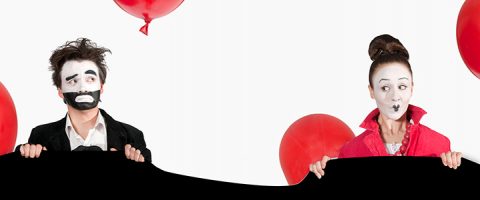 Kaksi valkoisella kasvomaalilla ja ilmeikkäällä meikillä varustettua miimikkoa seisoo erillään toisistaan ja pitelee mustaa liinaa. Vasemmalla oleva mies näyttää huolestuneelta, hänellä on musta puku. Oikealla oleva nainen näyttää yllättyneeltä, punaisiin pukeutuneena. Heidän takanaan leijuu punaisia ilmapalloja.
