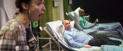 Etualalla seisoo hämmästynyt nainen, ja hänen takanaan on kaksi miestä sairaalasängyssä; toinen mies näyttää myös järkyttyneeltä, ja toinen lukee rauhallisesti sanomalehteä.