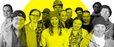 Erilainen joukko hymyileviä nuoria, joilla on hattuja, silmälaseja tai työasuja, seisoo yhdessä suuren keltaisen ympyrän edessä poseeraamassa ryhmäkuvaa varten.