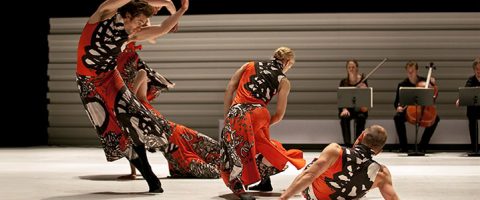 Kolme rohkeisiin mustiin, valkoisiin ja punaisiin pukuihin pukeutunutta tanssijaa tekee näyttämöllä ilmeikkäitä liikkeitä, kun taas kolme taustalla istuvaa muusikkoa soittaa jousisoittimia.