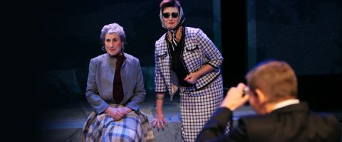 Lavalla poseeraa kaksi vintage-vaatteisiin pukeutunutta naista; toinen istuu ruutupeitto sylissään, toinen seisoo aurinkolasit ja huivi päässään. Heitä vastassa on pukumies, jolla on kamera kädessään kuin valokuvaa ottaessaan.