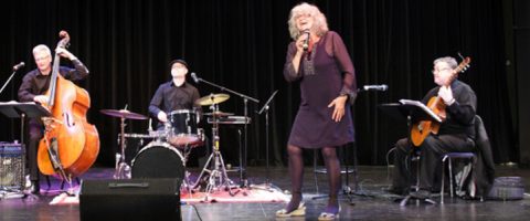 Nainen laulaa lavalla mikrofoniin, ja häntä säestää kolme muusikkoa, jotka soittavat kontrabassoa, rumpuja ja kitaraa, kaikki pukeutuneina mustaan ja taustana on tumma verho.