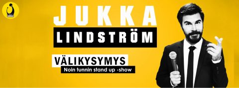 Pukumies, jolla on mikrofoni kädessään ja osoittaa ylöspäin, seisoo keltaisen taustan ja lihavoidun tekstin edessä: "Jukka Lindström Välikysymys Noin tunnin stand up -show." Vasemmassa yläkulmassa on pieni logo.