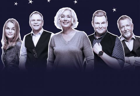 Viisi aikuista, kolme miestä ja kaksi naista, seisovat hymyillen rivissä tummansinisellä taustalla, jossa on valkoisia tähtiä. He vaikuttavat ystävällisiltä ja itsevarmoilta, ja he ovat pukeutuneet rentoon ja puoliviralliseen asuun.