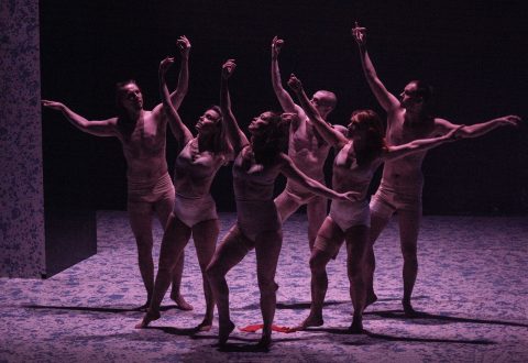 Kuusi tanssijaa violetissa valaistuksessa lavalla