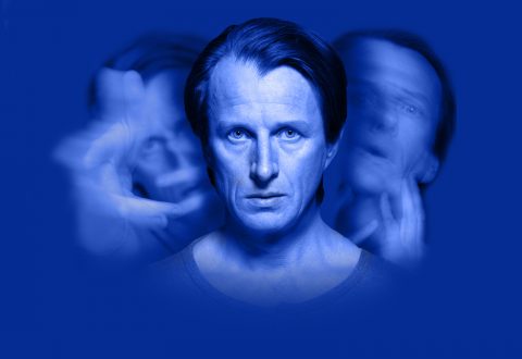 Keskellä on terävästi fokusoitu mies, jolla on vakava ilme, kun taas kaksi epätarkkaa, aavemaista versiota hänestä näkyy molemmilla puolilla sinistä taustaa vasten, mikä viittaa hämmennykseen, moninaisiin tunteisiin tai jakautuneeseen mieleen.