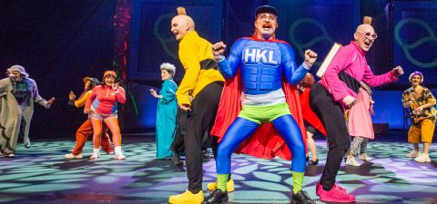 Vilkas lavaesitys sisältää värikkäitä, omalaatuisia pukuja; supersankariksi pukeutunut henkilö, jonka rinnassa lukee "HKL", seisoo keskellä, ja häntä ympäröivät energiset tanssijat kirkkaissa peruukissa ja omituisissa asuissa.