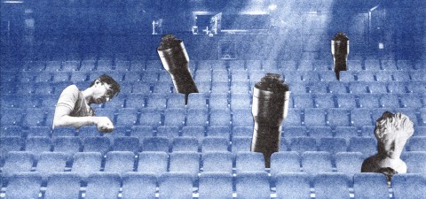 Sinisävyinen teatteri, jossa on tyhjiä istuimia, muutama ihminen istuu pää alaspäin ja joistakin istuimista nousee esiin suuria mikrofoneja. Tunnelma on surrealistinen ja unenomainen.