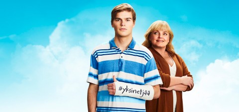 Poika sinivalkoraidallisessa pikeepaidassa ja käsi kipsissä katsoo kameraan. Hiukan pojan takana, pojan äiti katsoo hymyillen poikaansa käden puuskassa. Taustalla näkyy sininen taivas ja vähän pilviä.