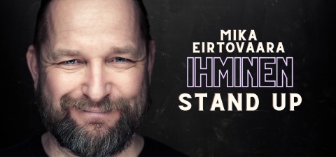 Hymyilevä parrakas mies tummaa taustaa vasten. Teksti hänen vieressään kuuluu: Mika Eirtovaara Ihminen seisomaan.