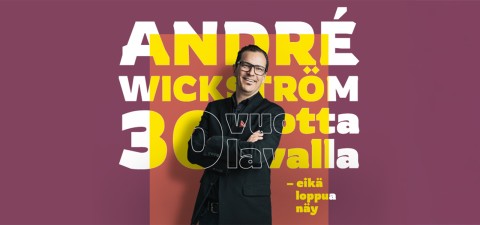 Hymyilevä mies, jolla on silmälasit ja ristissä olevat kädet, seisoo vaaleanpunaisella taustalla olevan André Wickström 30 vuotta lavalla - eikä loppua näy -tekstin edessä.