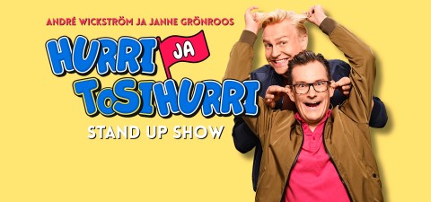 Kaksi hymyilevää miestä poseeraa leikkisästi keltaista taustaa vasten: "André Wickström ja Janne Grönroos, Hurri ja TosiHurri, Stand Up Show." Toinen mies tekee pupunkorvat toisen pään taakse.